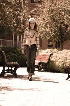 Twenty something fashion model walking on a paved sidewalk in a montreal park