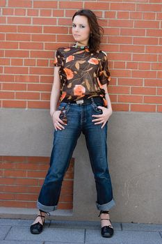 Twenty something fashion model giving a piercing look to the camera while hanging on a brick wall