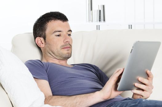 attractive relaxed and positive man is surfing on his tablet