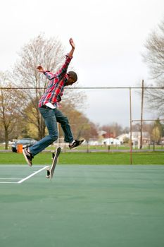 A skateboarder performing jumps or ollies on some tennis courts.  Slight motion blur showing the movement on the arms and legs.