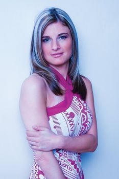 Thirty something women leaning on wall with pink top giving a shy simle shy smile to the camera