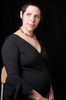Sitting portrait of a late twenty pregnant women looking to the far left