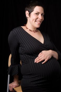 Sitting portrait of a late twenty pregnant women with a big smile