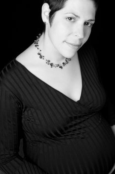 black and white sitting portrait of a late twenty pregnant women with shy smile