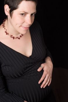 Portrait of a late twentie pregnant women looking at the camera with a shy smile