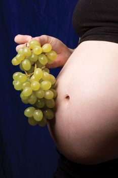 Close up of a pregnant belly with grapes near the belly button