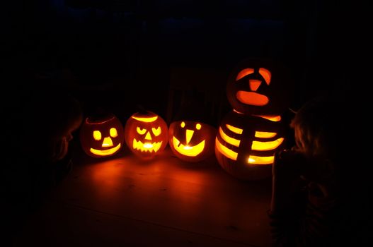 Four halloween pumpkins being watched by two boys