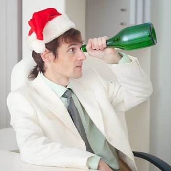 The drunk man in a Christmas cap plays the fool with a bottle