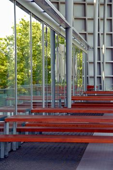 Modern building of glass and metal and wooden tables and benches
