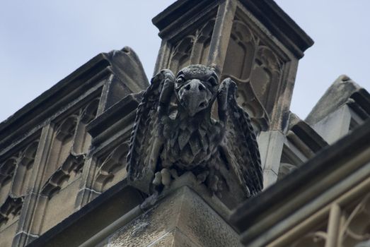 Grotesque stone sculpture on the side of a gothic revival building