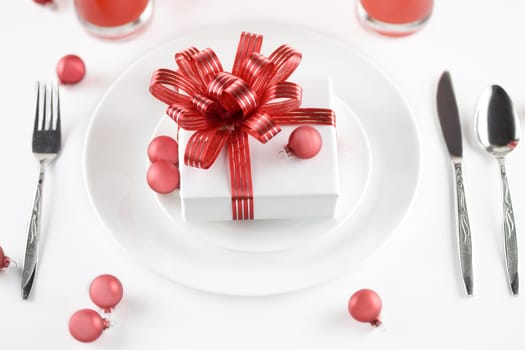 White present with red ribbons on a dinner plate, christmas theme