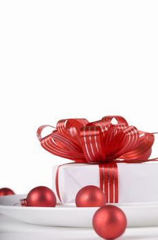 White present with red ribbons on a dinner plate, christmas theme