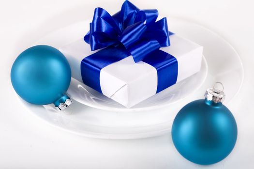 White present with blue ribbons on a dinner plate, christmas theme