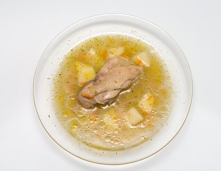 Chicken soup in a transparent plate a close up.