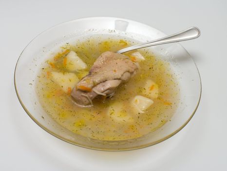 Chicken soup in a transparent plate a close up.