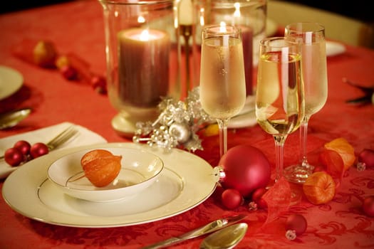 Elegant Christmas table setting in red and gold colors, with red Japanese lantern flower as focal point