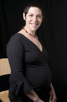 Sitting portrait of a late twenty pregnant women with a great big smile