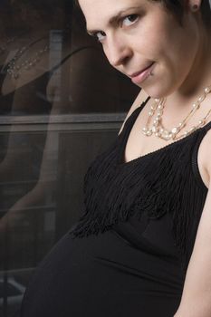 Late twentie pregnant woman in old fashion evening dress with urban background