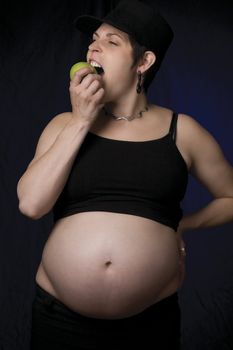 Portrait of a late twentie pregnant women eating an apple
