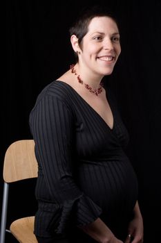 Sitting portrait of a late twenty pregnant women with a great big smile