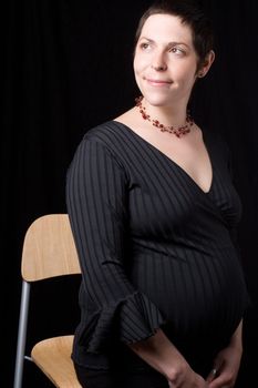 Sitting portrait of a late twenty pregnant women looking perky with a great big smile