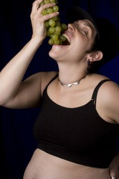 Twenty something pregnant women with boyish look eating green grapes