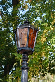 Street multi-coloured lantern removed against autumn foliage of trees