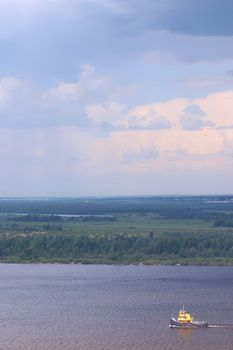 The ship on the river on the blue cloudy sky