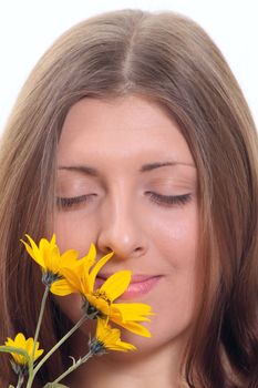 Portrait of the nice girl inhaling aroma of a yellow flower removed close up