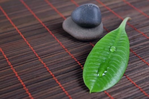 Stones for spa with green sheet on a bamboo napkin removed close up