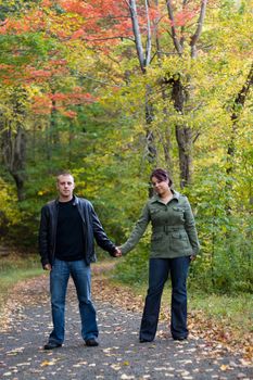 A young happy couple on a path in the woods during Autumn.
