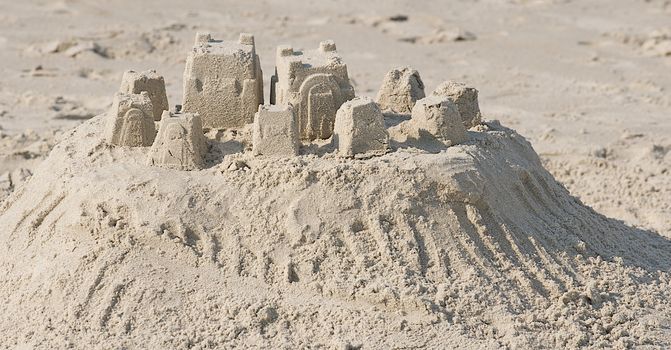 Sand sculpture of a small town created by children at the beach.