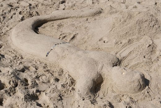Interesting and artistic sand sculpture of a merman embedded on the beach at Emerald Isle, North Carolina.