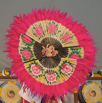 Women hold fans together in a circle during a traditional Korean fan dance.