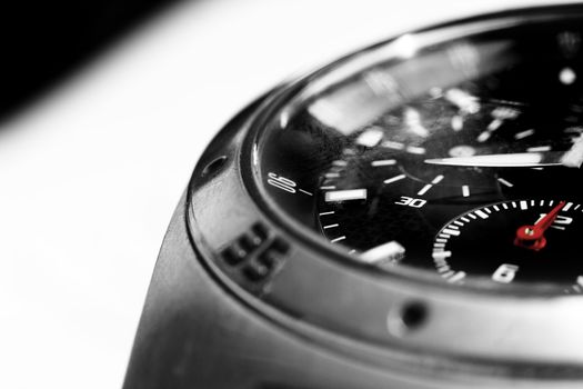 High contrast image of a men's wristwatch close up, black and white with red hads.