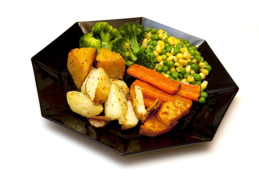 Several servings of backed vegetables on a black plate