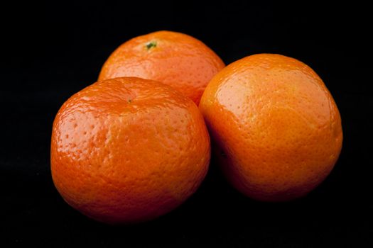 Three bright juicy mandarines isolated against black