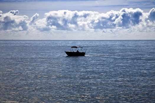 A small boat alone out on the ocean.