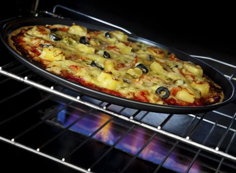 Delicious pizza cooking in a gas oven