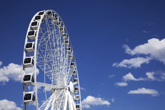 A large white ferris wheel against a beautiful blue sky.