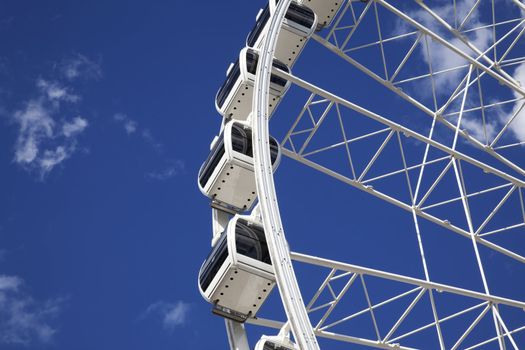 A detailed view of a large white ferris wheel against a beautiful blue sky