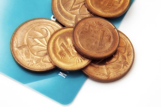 Small change coins sitting on a blue credit card, against white.