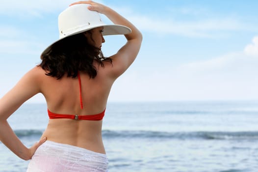 The woman on sea coast in a hat. The rear view