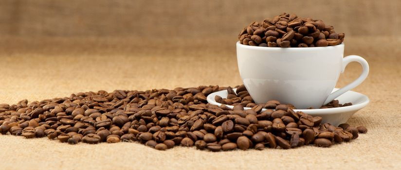 White cup with coffee grains. Grunge background