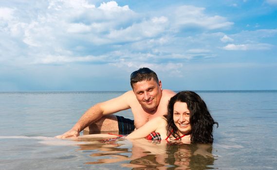 Young pair in the sea. Against the blue sky