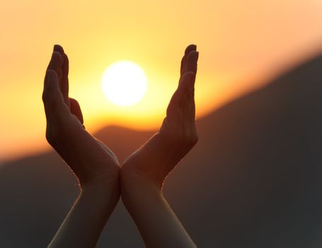 Decline in hands. A sunset on a background of the lifted female hands