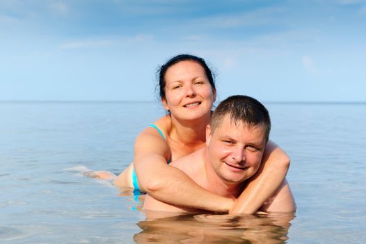 Happy young couple in the sea. Lie in water