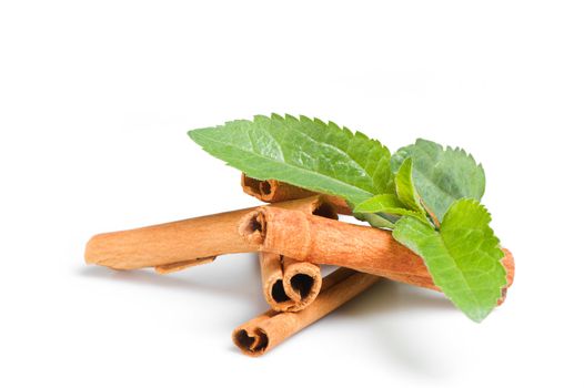 Cinnamon and green leaves. A heap of sticks of cinnamon on a white background