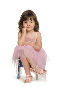 Pretty the little girl sits on a stool. It is isolated on a white background