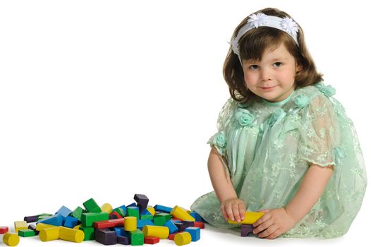 The lovely little girl plays colour wooden cubes. It is isolated on a white background